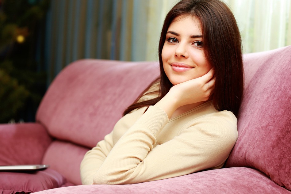Young beautiful happy woman sitting on the sofa at home